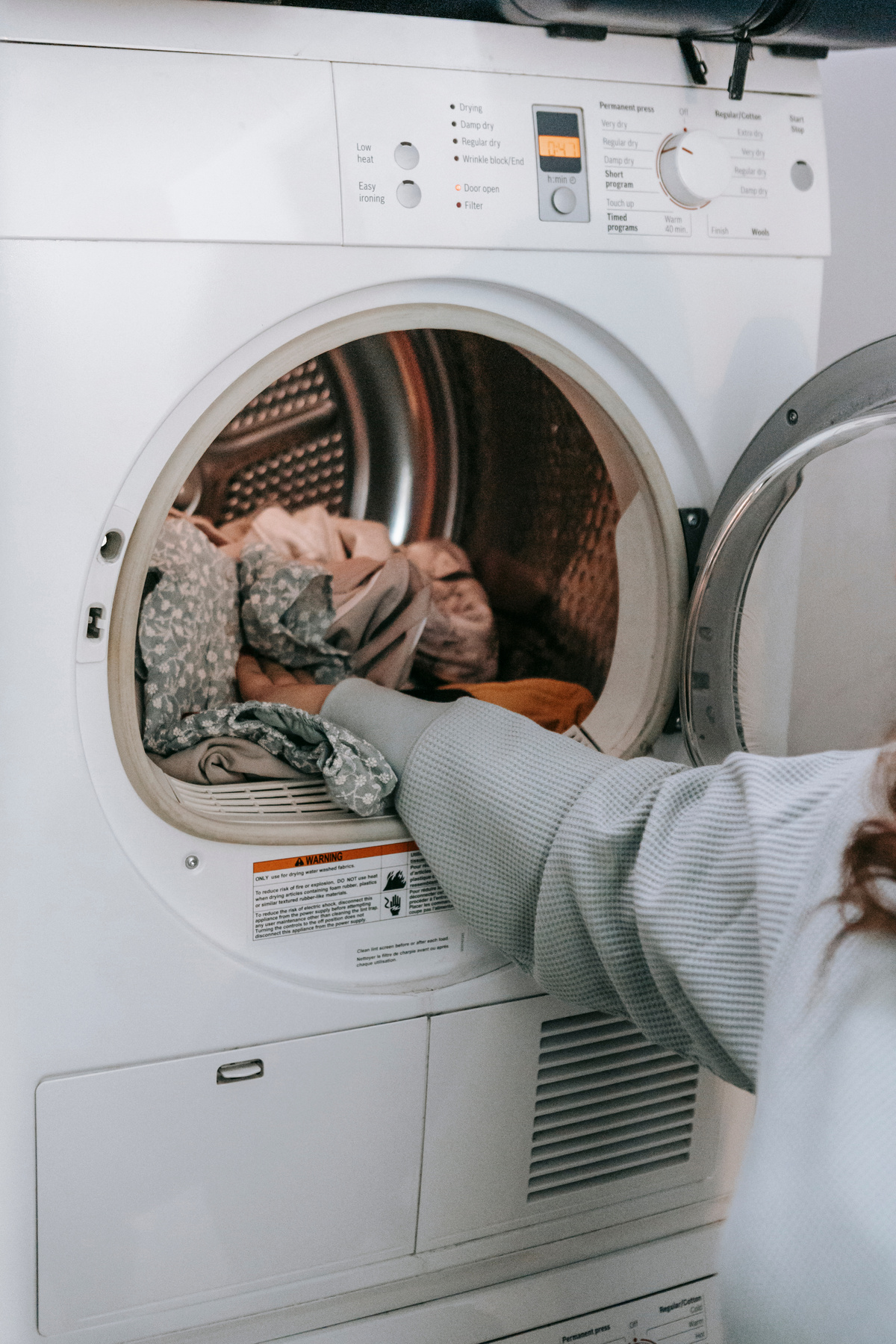 Anonymous woman loading clothes in washing machine